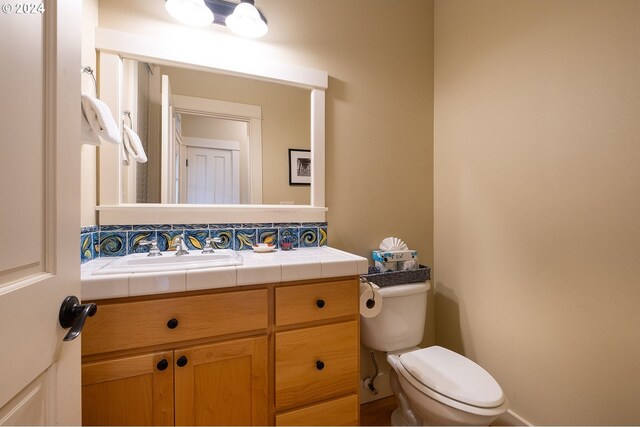 bathroom featuring tasteful backsplash, toilet, and vanity