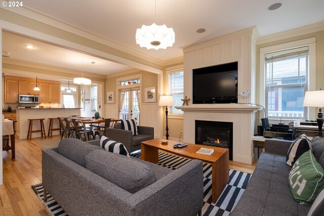 living room featuring crown molding, light hardwood / wood-style floors, and plenty of natural light