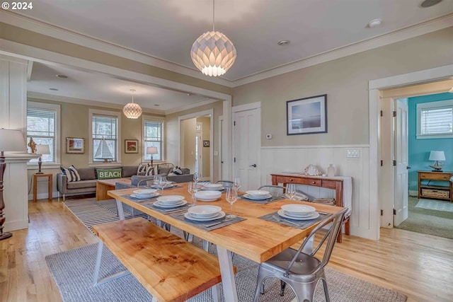 dining space featuring light wood-style floors, wainscoting, and crown molding