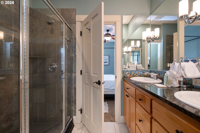 bathroom featuring tile patterned flooring, a shower with door, ceiling fan with notable chandelier, and vanity