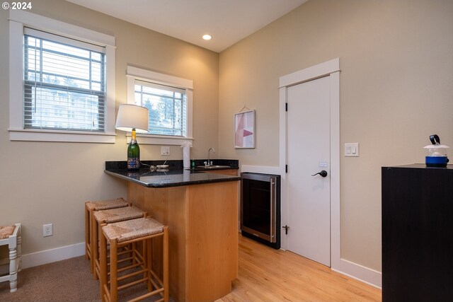 bar with light wood-type flooring, wine cooler, and sink