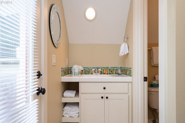 half bath featuring vaulted ceiling, vanity, and toilet