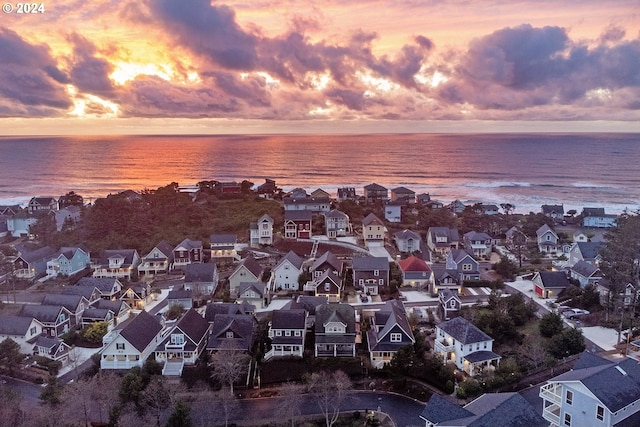 aerial view at dusk featuring a residential view and a water view