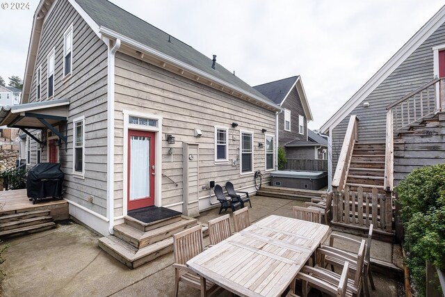 rear view of property featuring a patio and a hot tub