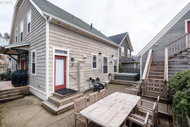 back of property with a patio, stairway, a hot tub, entry steps, and outdoor dining space