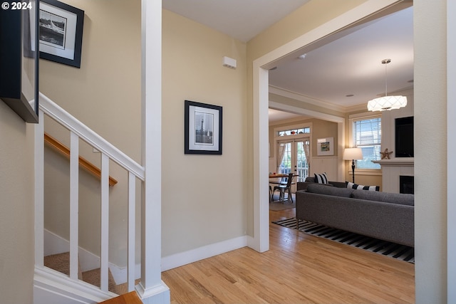 corridor with wood finished floors, baseboards, stairs, french doors, and ornamental molding