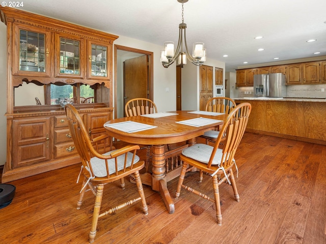 dining area with light hardwood / wood-style flooring and an inviting chandelier