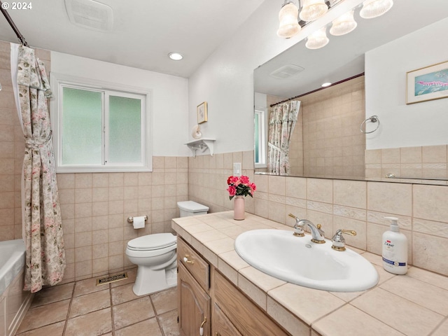 full bathroom featuring shower / bathtub combination with curtain, tile patterned floors, toilet, vanity, and tile walls