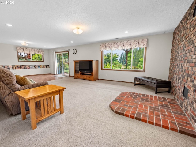 living room featuring carpet, a textured ceiling, and brick wall