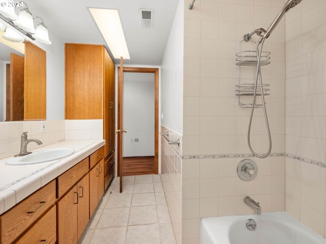 bathroom featuring vanity, tiled shower / bath combo, tile patterned floors, and tile walls