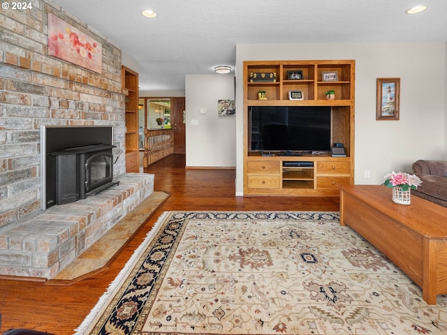 living room featuring wood-type flooring, a textured ceiling, and a wood stove