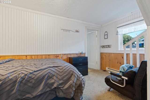 carpeted bedroom with a baseboard heating unit, ornamental molding, and a textured ceiling