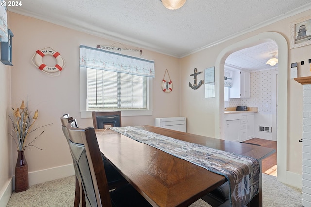 carpeted dining area featuring crown molding and a textured ceiling