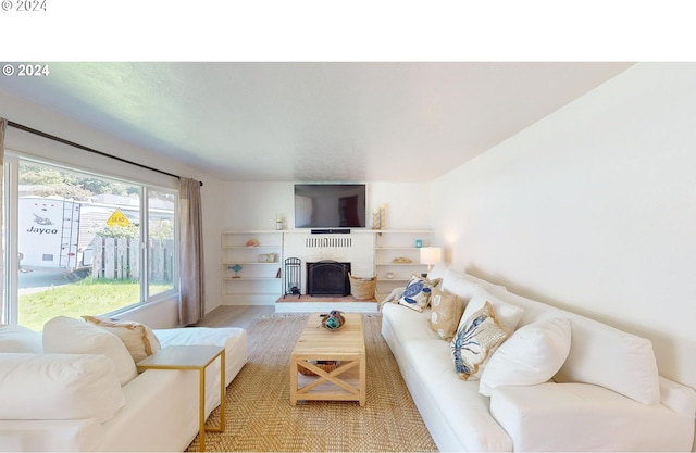 living room with a brick fireplace and hardwood / wood-style flooring