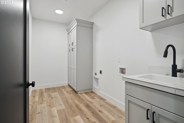 clothes washing area with cabinets, sink, hookup for a washing machine, light wood-type flooring, and hookup for an electric dryer