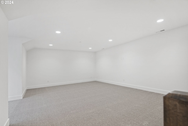 unfurnished room featuring light carpet and vaulted ceiling