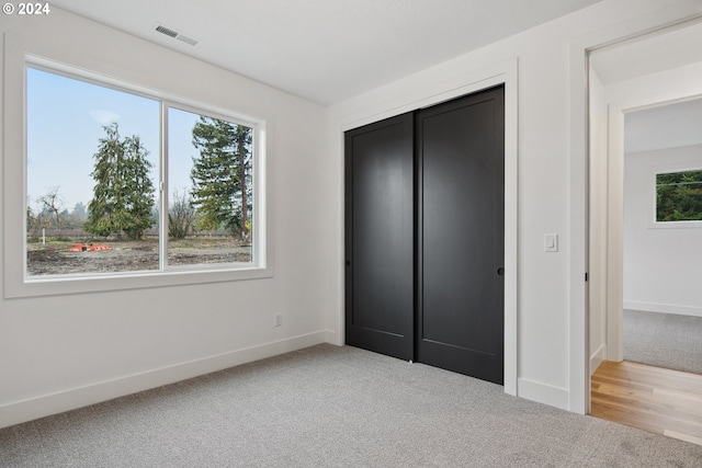 unfurnished bedroom with a closet and light colored carpet