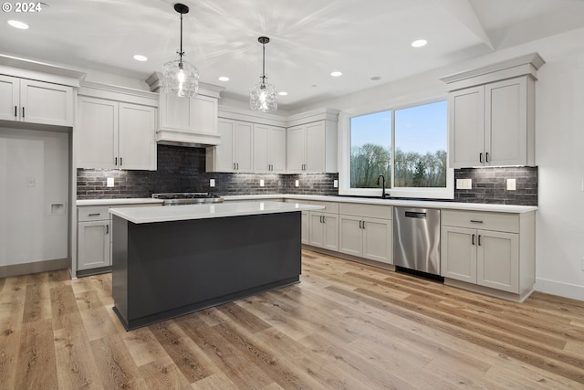 kitchen with appliances with stainless steel finishes, light wood-type flooring, pendant lighting, white cabinets, and a center island