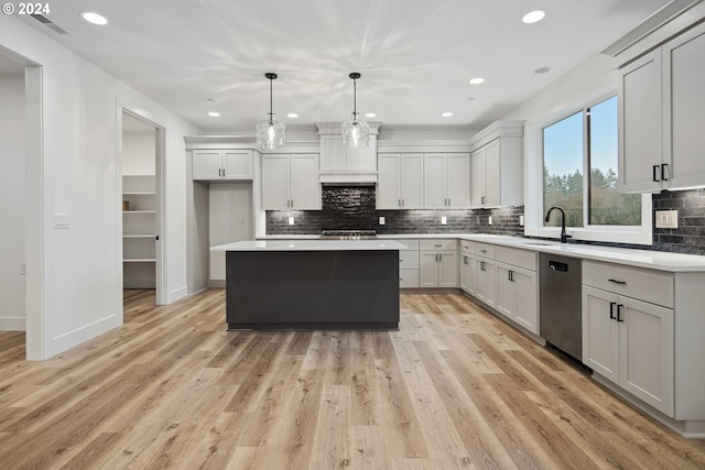 kitchen featuring a center island, stainless steel appliances, hanging light fixtures, and light hardwood / wood-style floors