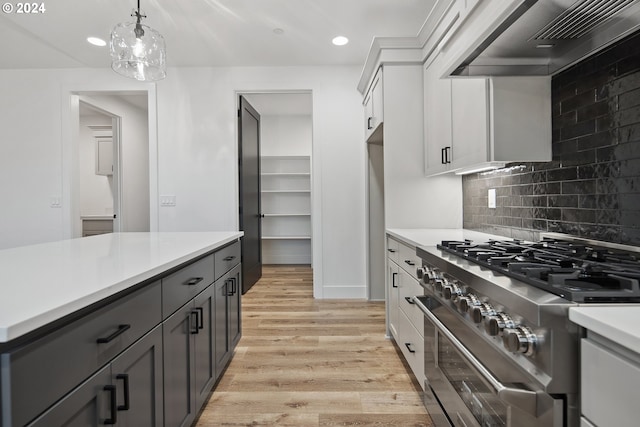 kitchen with premium range hood, stainless steel range, pendant lighting, light hardwood / wood-style flooring, and white cabinetry