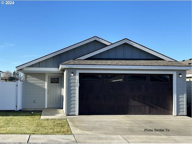 ranch-style home with an attached garage, board and batten siding, driveway, and fence