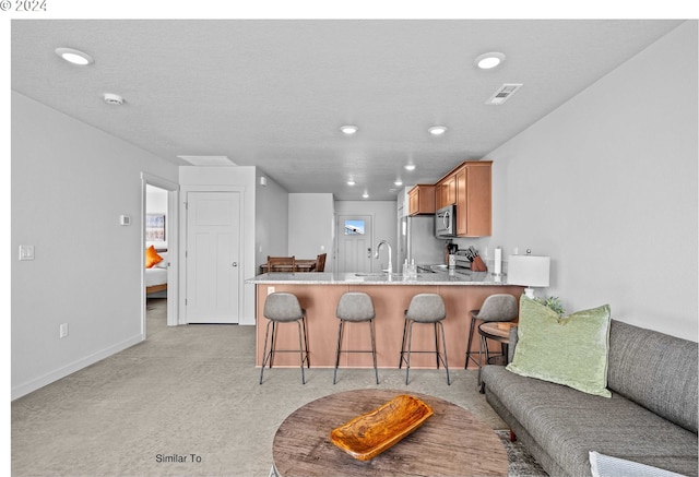 kitchen with visible vents, a peninsula, recessed lighting, stainless steel appliances, and a kitchen bar