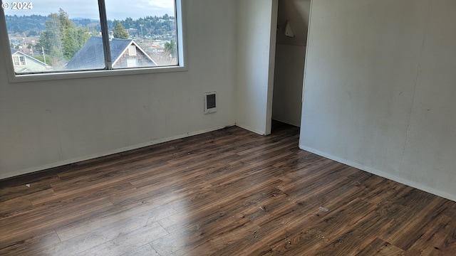 unfurnished room with heating unit and dark wood-type flooring