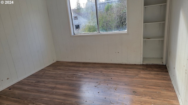 unfurnished room with dark hardwood / wood-style flooring and wooden walls