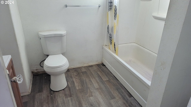 bathroom with hardwood / wood-style floors, toilet, and shower / bath combo with shower curtain