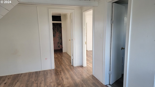 corridor with hardwood / wood-style floors and vaulted ceiling