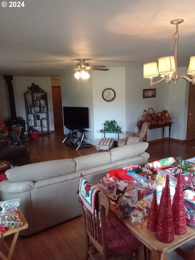 interior space featuring ceiling fan with notable chandelier, hardwood / wood-style flooring, and a wood stove