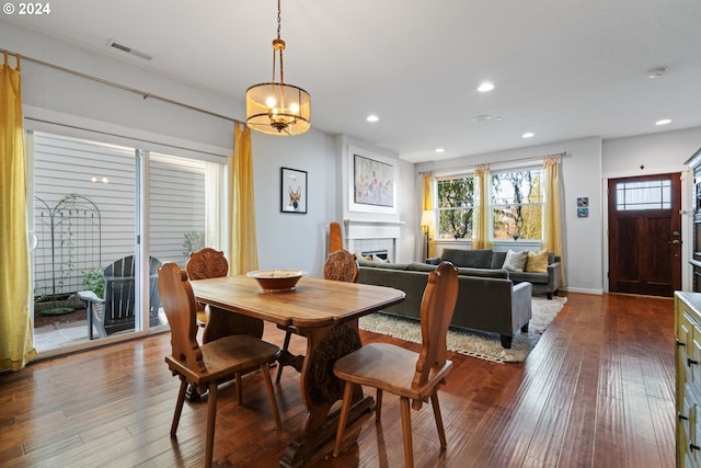 dining room with a tile fireplace, wood-type flooring, and a notable chandelier