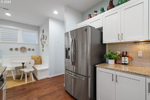 kitchen featuring backsplash, stainless steel refrigerator with ice dispenser, dark hardwood / wood-style floors, light stone counters, and white cabinetry