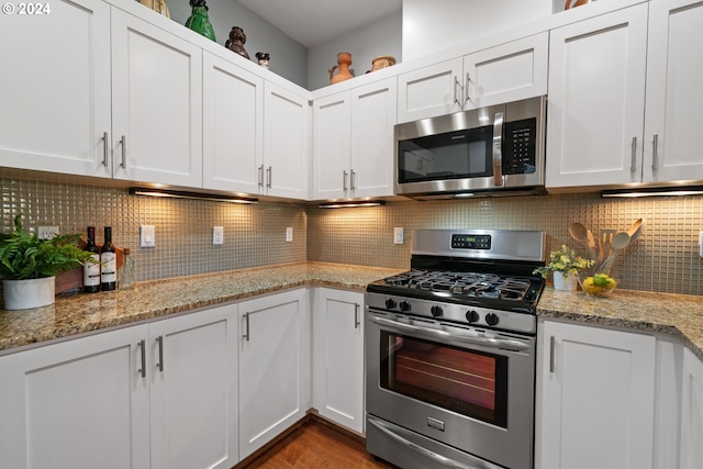 kitchen with white cabinets, backsplash, stainless steel appliances, and light stone counters