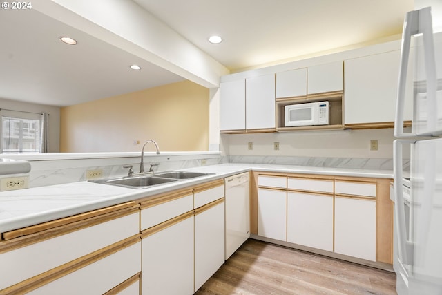 kitchen with kitchen peninsula, white appliances, sink, white cabinets, and light hardwood / wood-style floors