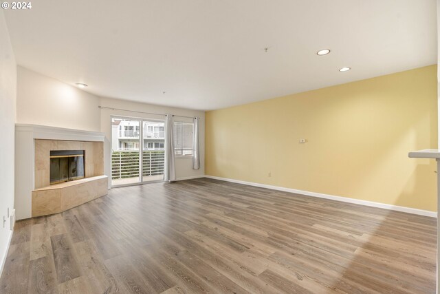 unfurnished living room with a tile fireplace and wood-type flooring