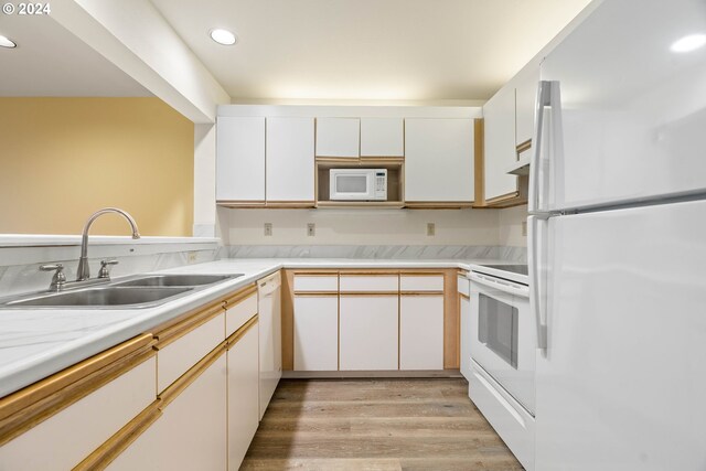 kitchen with white cabinets, white appliances, sink, and light hardwood / wood-style flooring