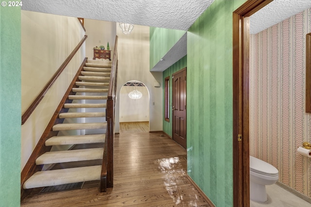 staircase with hardwood / wood-style floors and a textured ceiling