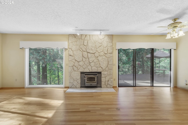 unfurnished living room with a wood stove, light wood-type flooring, and plenty of natural light