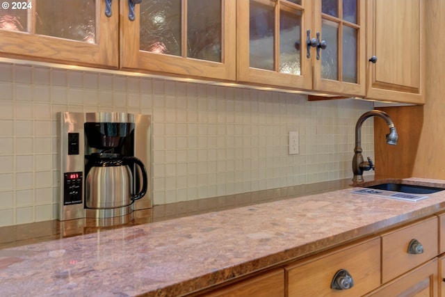 kitchen featuring sink, light stone counters, and tasteful backsplash