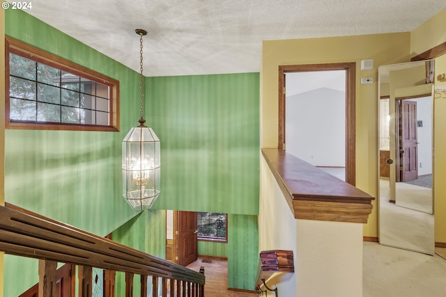 stairway with a textured ceiling, vaulted ceiling, a notable chandelier, and carpet floors