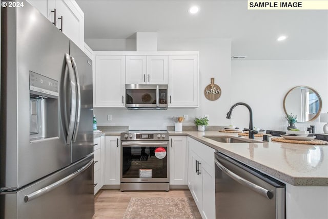 kitchen with light stone countertops, white cabinetry, sink, and appliances with stainless steel finishes