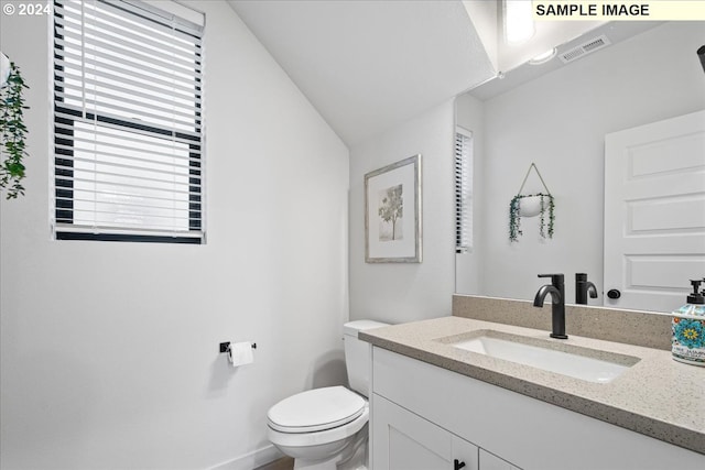 bathroom featuring vanity, toilet, and lofted ceiling