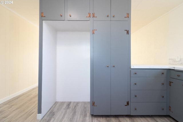 kitchen with gray cabinetry, wood walls, and light wood-type flooring