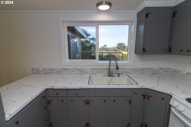 kitchen with gray cabinetry, sink, and white range