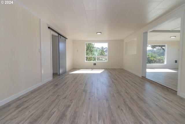 unfurnished room with a barn door and light hardwood / wood-style flooring