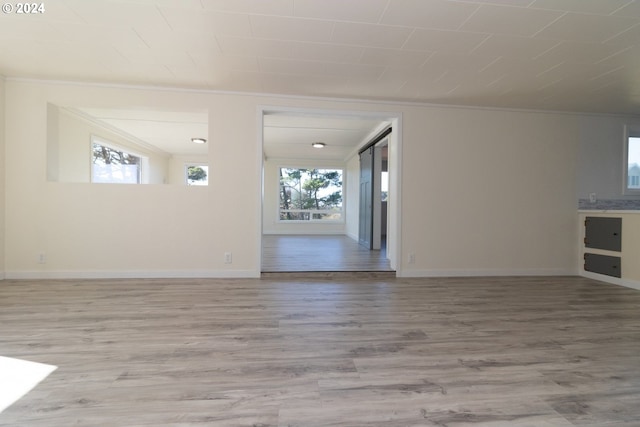 unfurnished living room with wood-type flooring and ornamental molding