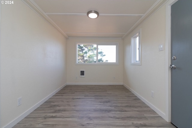 unfurnished room with crown molding, baseboards, light wood-type flooring, and heating unit