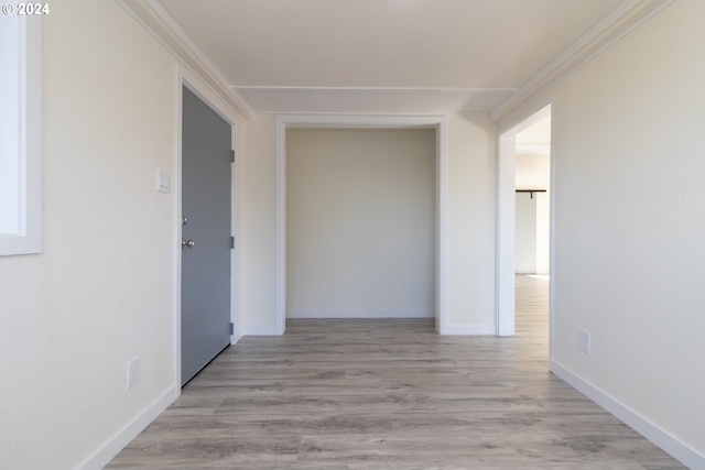 corridor with light hardwood / wood-style floors and ornamental molding