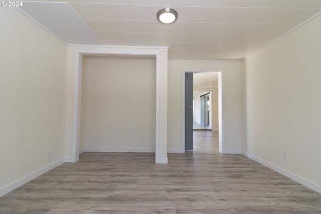 empty room featuring ornamental molding, baseboards, and wood finished floors